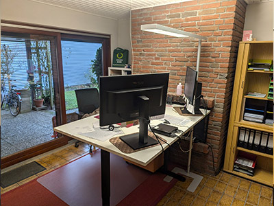 Heller Büroraum der Steuerring-Beratungsstelle Flensburg mit Schreibtisch, zwei Monitoren und einem bodentiefen Fenster.