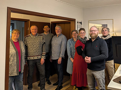 Team der Steuerring-Beratungsstelle in Flensburg mit acht Personen im Büro, gemeinsam in die Kamera blickend, vor hellen Wänden und Schreibtisch
